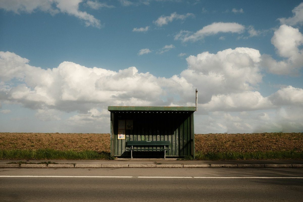 Abribus isolé au bord d'une route de campagne sous un ciel nuageux