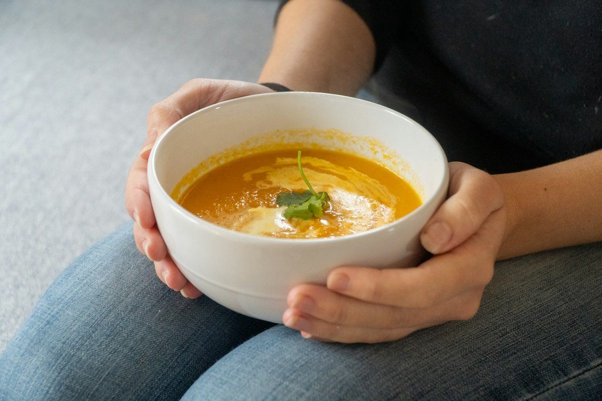 Mains qui tiennent un bol de soupe de potiron