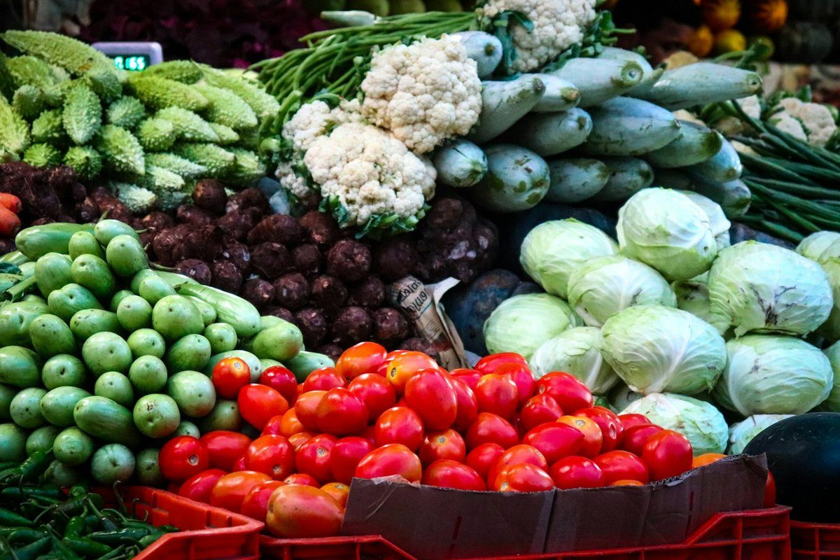 Étal de légumes de saison sur un marché : choux, chou-fleur, tomates et courgettes