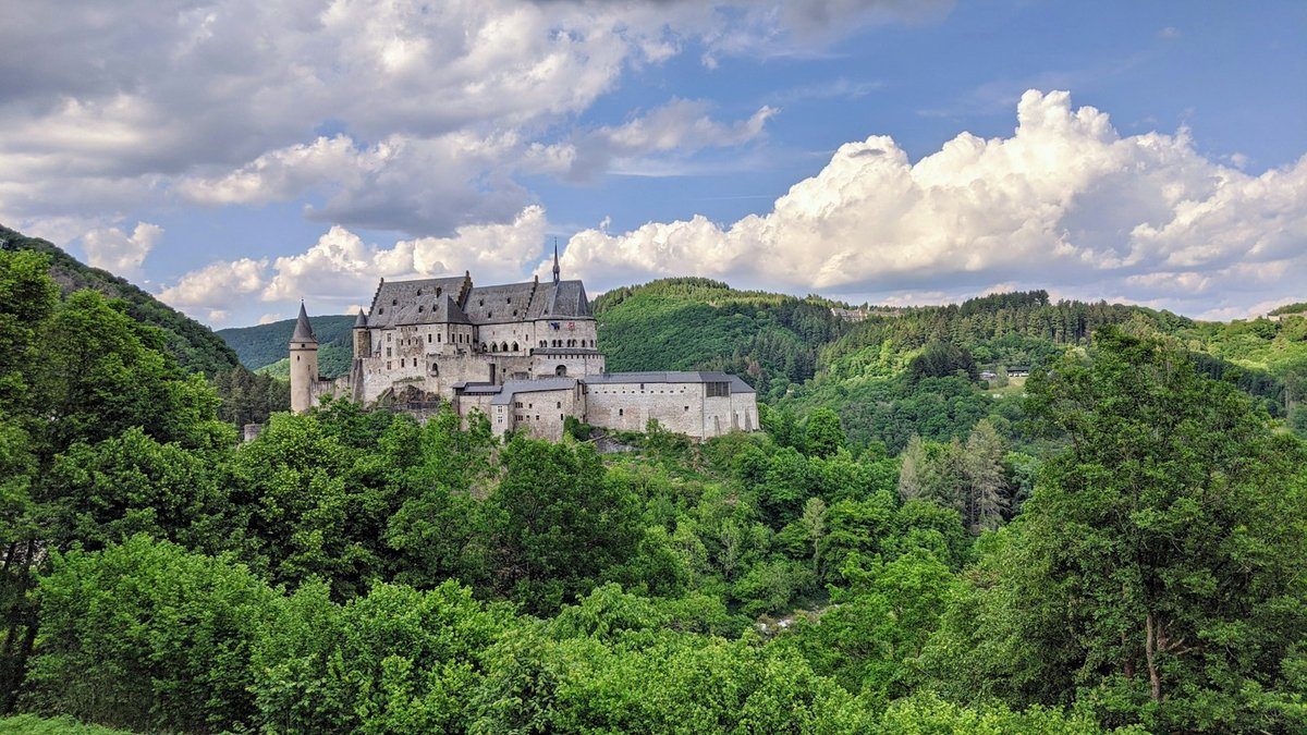 Château de Vianden au sommet d'une colline boisée, sous un ciel nuageux