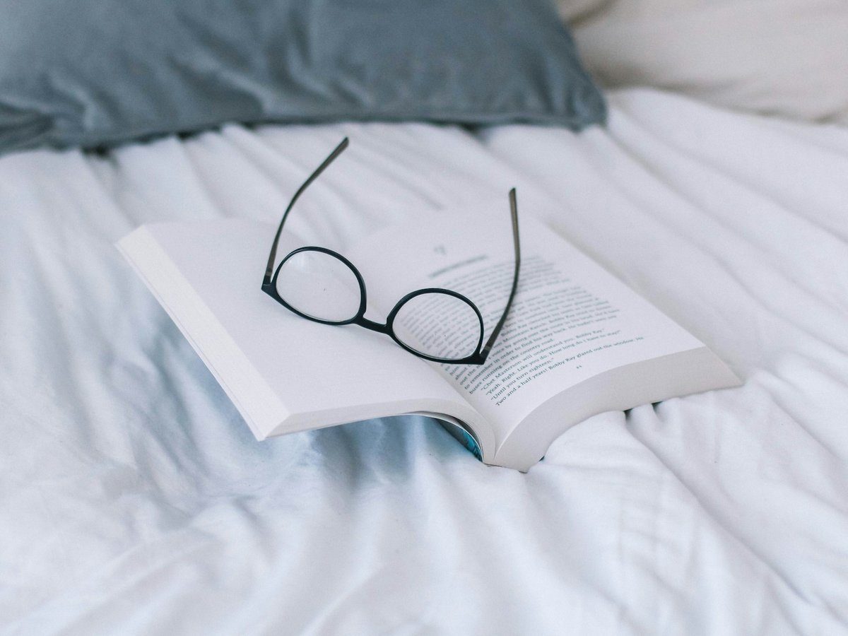 Lunettes posées sur un livre ouvert, sur un lit
